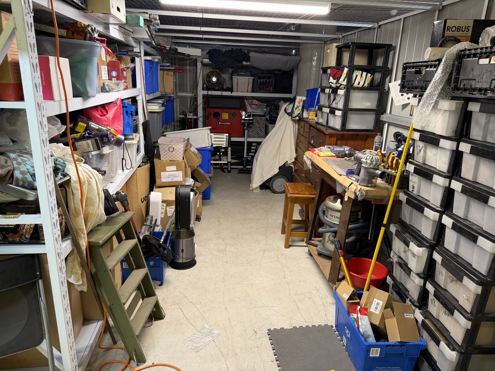 Eddie's Dyson parts store — a stick vacuum motor on the bench beside walls of model-labelled parts bins